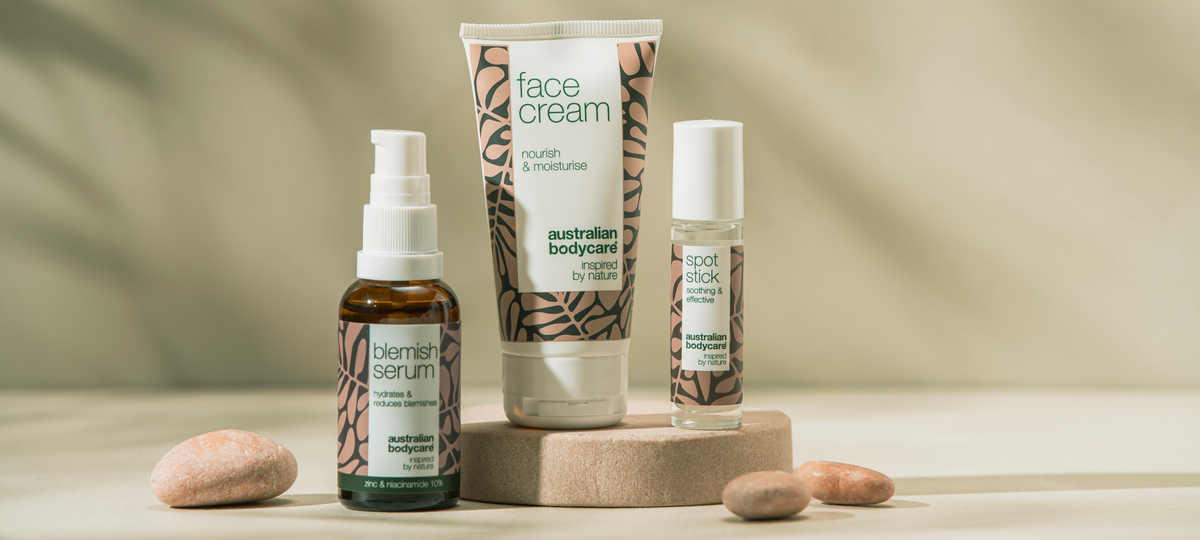 Blemish Serum, Face Cream a Spot Stick od Australian Bodycare v béžovoružovom obale na kamennom podstavci, okolo okruhliaky.