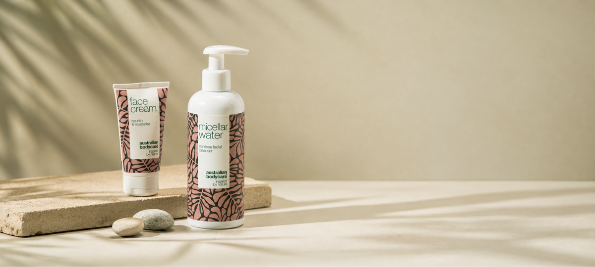Face Cream a Micellar Water od Australian Bodycare v béžovom obale na kamennom kvádri na svetlom pozadí s tieňmi listov.