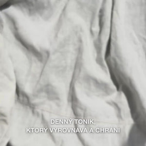 Detail ruky, ktorá nakvapká niekoľko kvapiek číreho, vodnatého Face Tonic s tea tree olejom na tampónik a potom ho jemne potiera po čistej pokožke tváre: ľahká, osviežujúca tekutina upokojuje, hlboko čistí, hydratuje a zanecháva pleť obnovenú a pripravenú na krém.