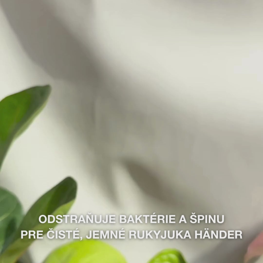 Detail ruk, ktoré dávkujú do dlane číre, svetlomodré, penivé tekuté mydlo s Tea Tree Oil a potom ho jemne vmasírujú do dlaň, hřbete rúk a medzi prsty — jemná pena odstraňuje baktérie a nečistoty, zároveň zjemňuje a hydratuje pokožku.